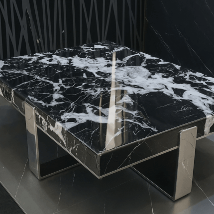 Table basse avec plateau rock slab texturé brillant et piètement en métal noir mat.
